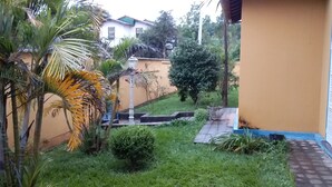 Ein Garten mit Palmen, einem Weg und einem Gebäude mit gelber Wand und blauen Verzierungen.