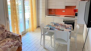 Eine moderne Küche mit Essbereich, inklusive Tisch mit Zeitschriftenheft, weißen Stühlen und einer Schiebeglastür zum Außenbereich.