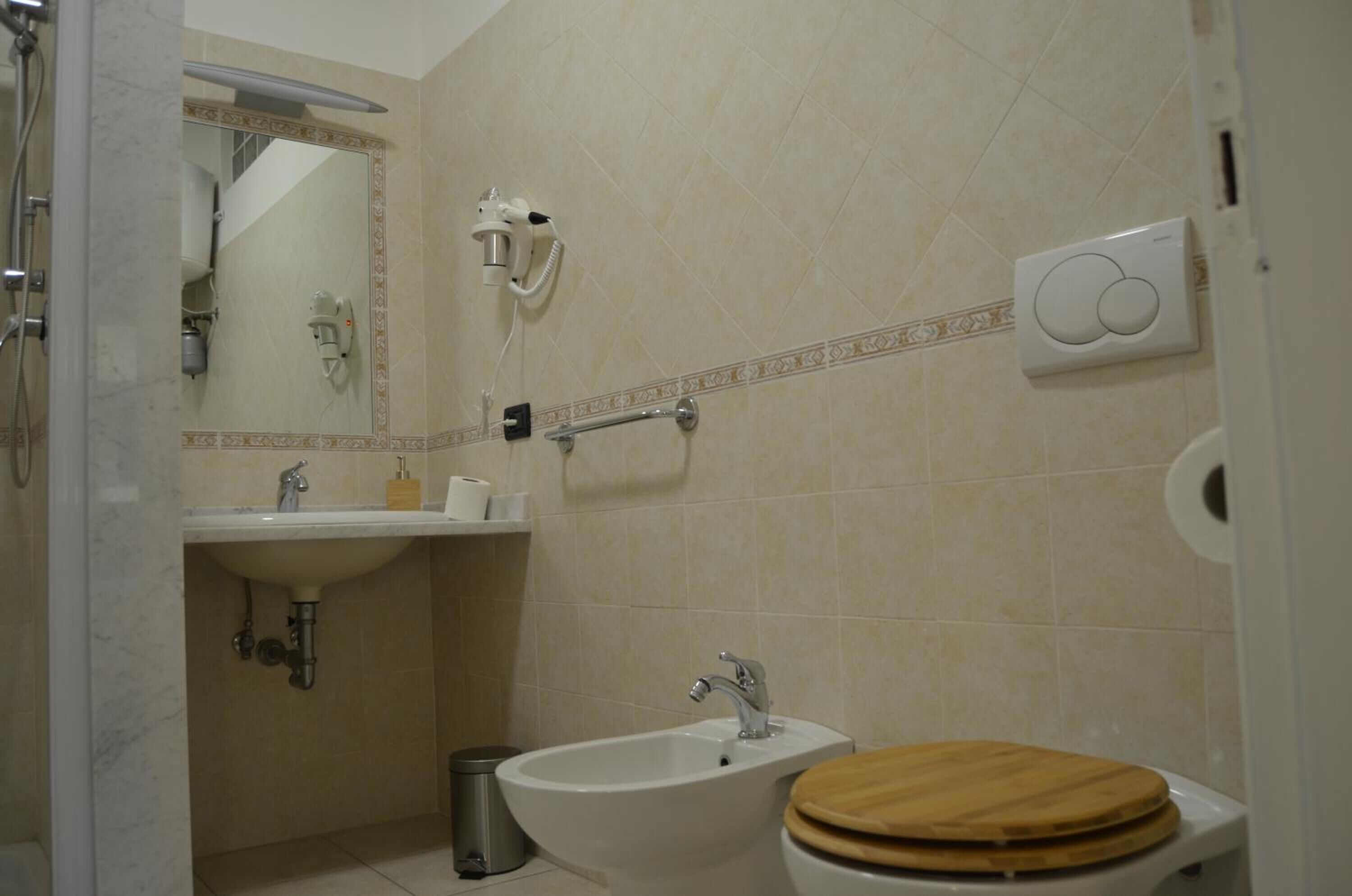 Un baño con lavamanos, espejo, inodoro y ducha.