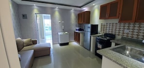 Compact kitchen with gas stove, microwave, refrigerator, and sink.