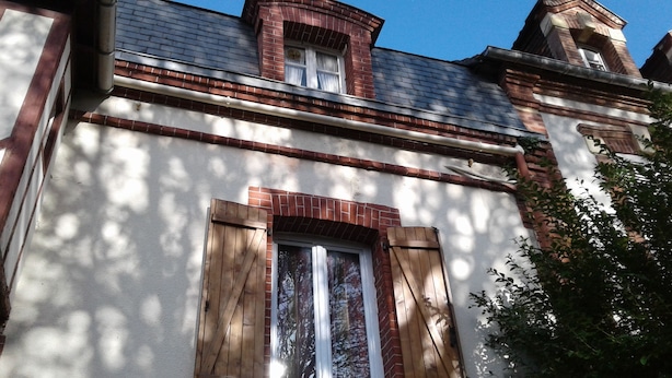 A building with a brick facade, a window with wooden shutters, and a chimney. - Apartment 2 Ch near the beach and downtown Houlgate. (Houlgate)