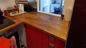 A compact kitchen with a microwave, toaster, and red cabinets. - Apartment 2 Ch near the beach and downtown Houlgate. (Houlgate)
