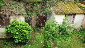 A rustic garden with a stone pathway leading to a small building with a thatched roof. - Apartment 2 Ch near the beach and downtown Houlgate. (Houlgate)