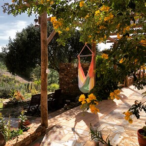 Un patio con una hamaca, pared de piedra y plantas en macetas.