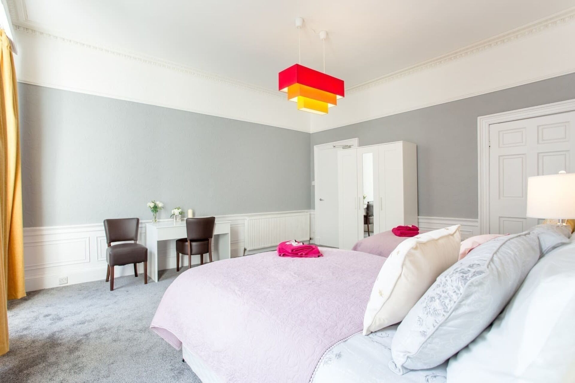 Ein Hotelzimmer mit einem großen Bett, einem Schreibtisch, zwei Stühlen und einem Kleiderschrank.