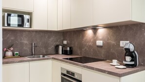 Eine moderne Küche mit Mikrowelle, Kaffeemaschine, Wasserkocher und Backofen.
