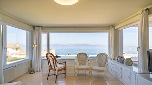 Amplia habitación con vistas al mar, un área de comedor con sillas, un sofá y un televisor.