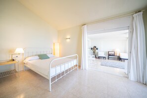 Une chambre moderne avec un lit, une table de chevet, une lampe et une vue sur un balcon.