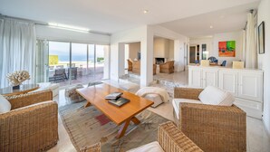 Un salón amplio con muebles de mimbre, una mesa de centro de madera y vistas al exterior.