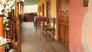A narrow corridor with wooden benches and a table, wooden doors, and a brick wall. - Moutainbike House (Calca)