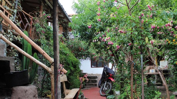 A narrow pathway leading to a traditional house with a motorcycle parked outside. - Moutainbike House (Calca)