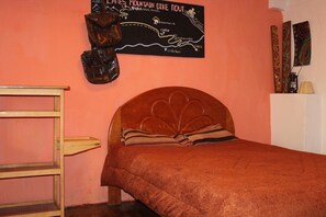 A bedroom with a wooden headboard, a map on the wall, and a shelf with decorative items. - Moutainbike House (Calca)