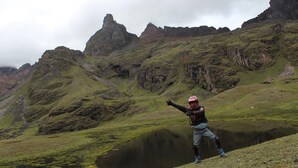 A person standing on a grassy hill with a lake and mountains in the background. - Moutainbike House (Calca)