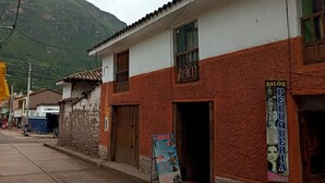 A building with a sign for 'SALÓN PELUQUERIA' and a menu board outside. - Moutainbike House (Calca)