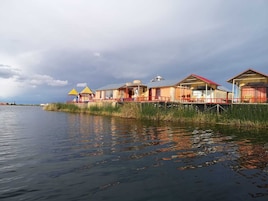A waterfront property with multiple buildings, some with red roofs and others with yellow roofs, connected by a wooden walkway over water.