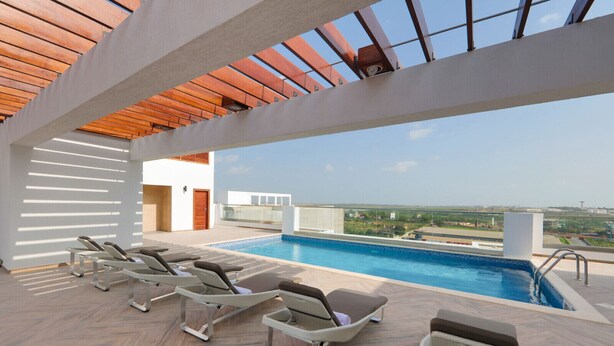 A rooftop pool area with lounge chairs and a clear view of the cityscape.