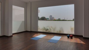 A spacious room with large windows, wooden flooring, and two yoga mats.
