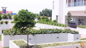 A modern outdoor area with planters, a tree, and a building with balconies.