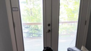 Une pièce dans laquelle se trouve un chien assis près d’une porte-fenêtre coulissante donnant sur un balcon.