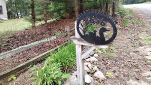 Une plaque métallique représentant un cygne et portant l’inscription « HANDLER’S CHAU », placée dans une zone boisée.
