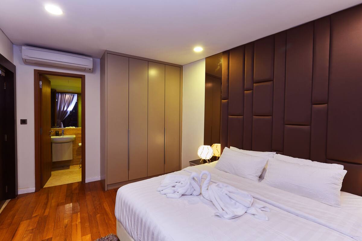 Ein Hotelzimmer mit einem großen Bett, einem Kleiderschrank, einem Badezimmer mit Waschbecken und einem Nachttisch mit Lampe.