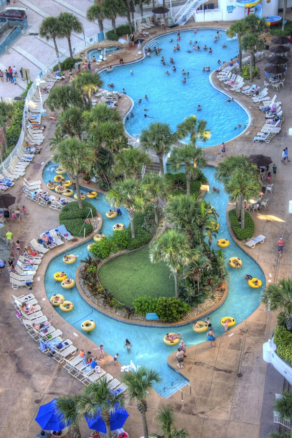 A large pool area with multiple lanes for water activities, surrounded by palm trees and sun loungers.