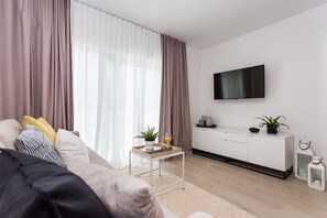 A modern living room with a sofa, a coffee table, a TV, and a white cabinet.