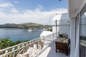 A balcony with a view of a lake and mountains, a white building, and a wooden bench. - Guest House Blanka (Okrug)