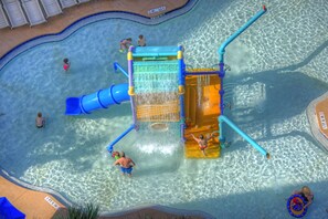 A water park with a clear pool, slides, and a play structure.
