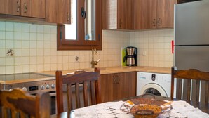 A kitchen with wooden cabinets, a stainless steel refrigerator, a washing machine, and a dining table with a basket of bread. - Melissi Villa, overlooking Vasiliki bay, close to the beach and other amenities! (Lefkada)