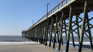 A pier extending into the ocean with a clear sky. - ~Carolina Tides~ Ocean View, Pier, Pool, Steps to the Beach and Restaurants! (Oak Island)