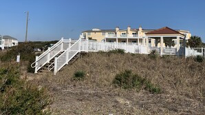 A beachfront property with a white staircase leading to a covered porch. - ~Carolina Tides~ Ocean View, Pier, Pool, Steps to the Beach and Restaurants! (Oak Island)