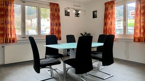 A conference room with a rectangular table, six black chairs, and two pendant lights. - Amazing Villa Littau  (Luzern)