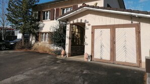 A two-story house with a garage, a large tree in front, and a parked car. - Amazing Villa Littau  (Luzern)