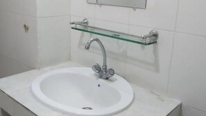 A bathroom with a white sink, a glass shelf above it, and a mirror on the wall. - Fairmont Guest House (Dhaka)