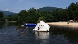 A water body with a floating structure, a sandy beach, and a forested area in the background. - Fantastic Post & Beam 5br Valley location near All Pool, Lake, Beach, Sleep 16 (Nellysford)
