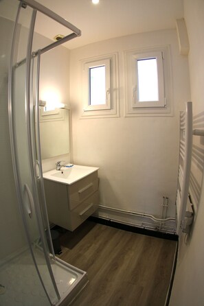 A bathroom with a glass shower enclosure, a white sink, and two windows. - Near Royan, 96m2 house with 500m2 enclosed garden - 3 beaches within 600m (Vaux-sur-Mer)