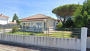 A residential property with a fenced yard, a house with a tiled roof, and a large tree. - Near Royan, 96m2 house with 500m2 enclosed garden - 3 beaches within 600m (Vaux-sur-Mer)