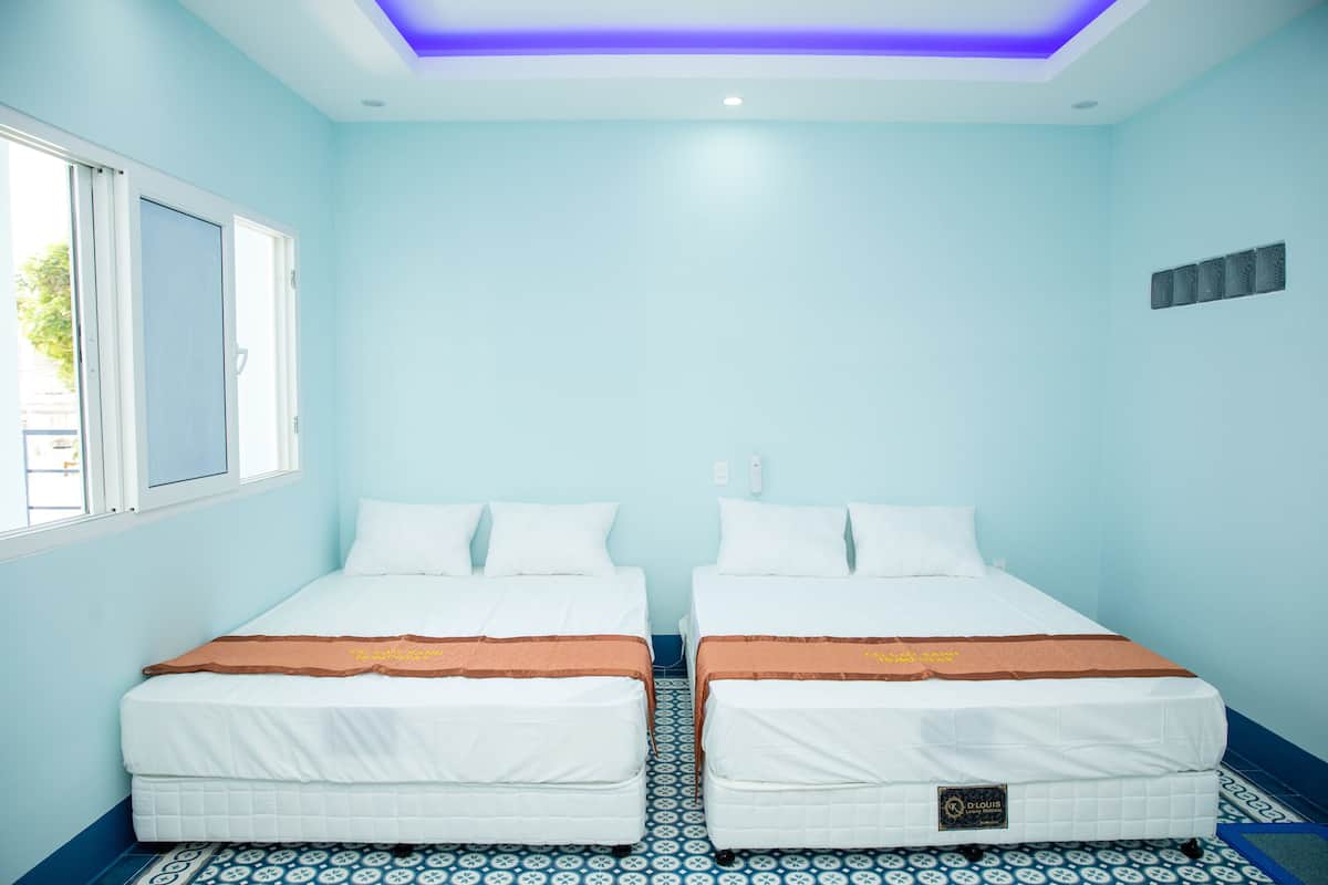 A room with two beds, a window, and a patterned floor.