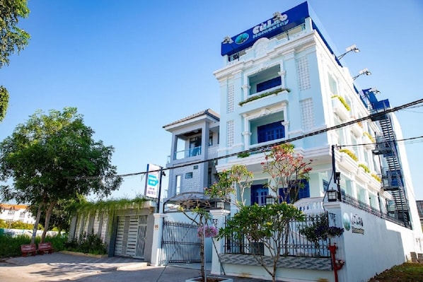 A hotel with a white facade and blue accents, featuring a prominent sign at the top.