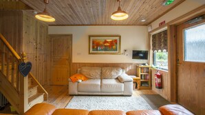 A cozy living room with a sofa, a coffee table, and a fireplace. There is a staircase with wooden railings leading to another level.