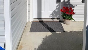 A white front door with a floral wreath, a doormat, and a potted red flower on the porch. - Parris Island Marine Corps Graduation PCS Orders Travel Nurses Beaufort Home (Beaufort)