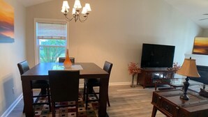 A dining area with a wooden table, chairs, a patterned rug, a chandelier, a television, and a cabinet. - Parris Island Marine Corps Graduation PCS Orders Travel Nurses Beaufort Home (Beaufort)