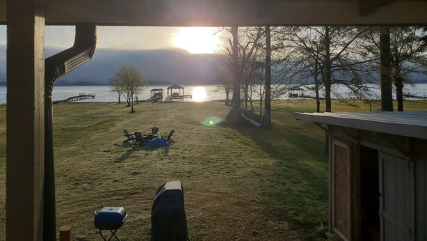 Espaço ao ar livre coberto com vista para um lago e um pôr do sol.