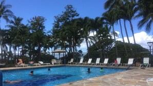 Una piscina con lettini da spiaggia e palme.