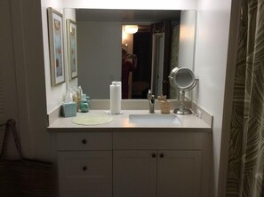 Un baño con tocador, espejo, toalla y retrete.