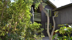 Un bâtiment en bois doté d’un balcon et d’un arbre devant.