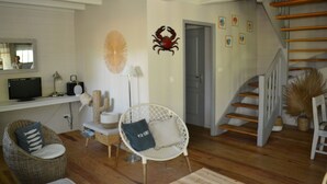 Un salon avec une télévision, un cactus, un fauteuil et un escalier.