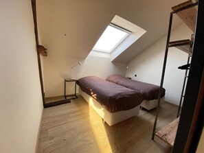A small, sloped ceiling room with two beds, a desk, and a skylight. - Sleeping in Medieval Ghent (Gent)