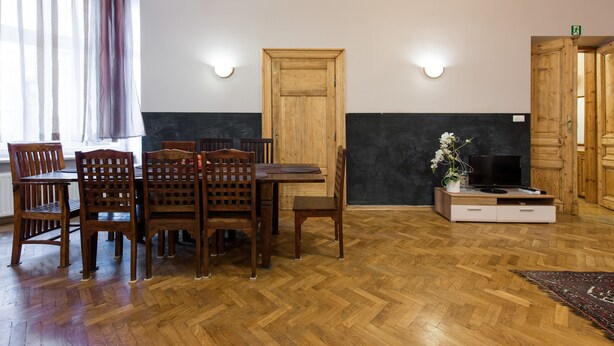 Een eetruimte met een houten tafel en stoelen, een houten deur, en een televisie op een meubel.